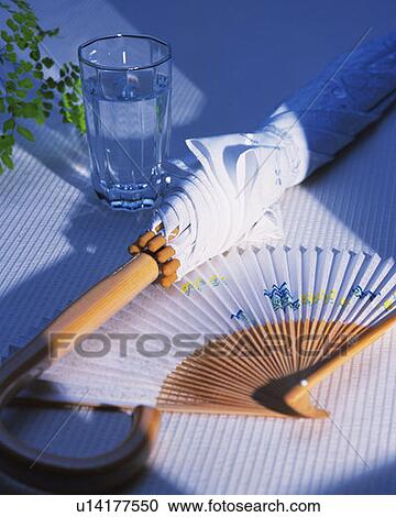 Stock Image - A glass of water, parasol and Japanese folding fan, high angle view, Japan. Fotosearch