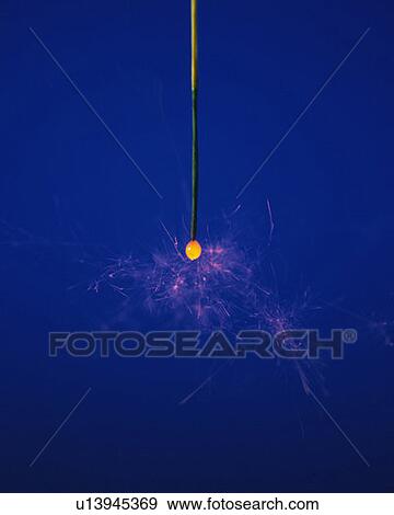 Stock Photo - A lighting sparkler, front view, close up, blue background. Fotosearch