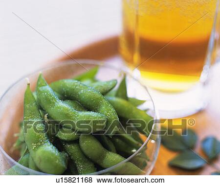 Stock Photo - Beer and boiled soybeans in glass bowl, high angle view, white background, differential focus. Fotosearch