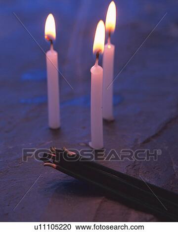 Stock Image - Burning candles and sticks of incense, high angle view, long exposure, differential focus. Fotosearch