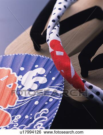 Stock Photograph - Japanese sandals, Japanese fan and towel, high angle view, gray background. Fotosearch
