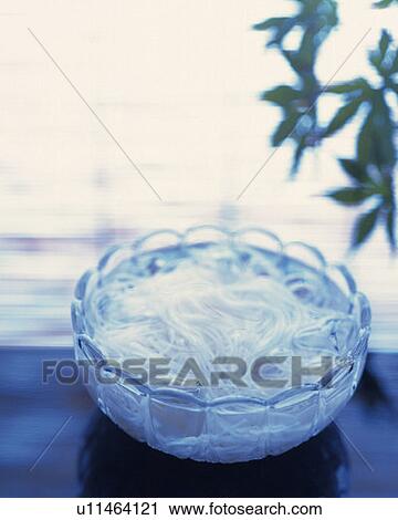 Stock Image - Noodles in ice water, high angle view, differential focus. Fotosearch