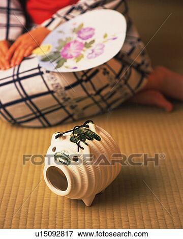 Stock Photo - Pig-shaped incense burner and woman in yukata sitting and holding a Japanese fan, front view, differential focus. Fotosearch
