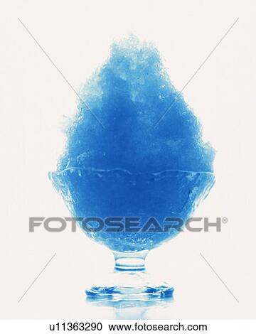Stock Image - Shaved ice with blue syrup, front view, white background, cut out. Fotosearch