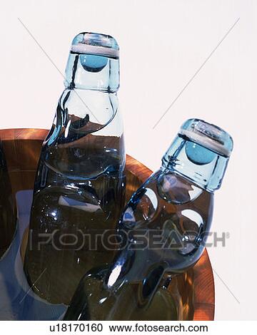 Stock Image - Soda bottles in tub of water, high angle view, close up, white background, cut out. Fotosearch
