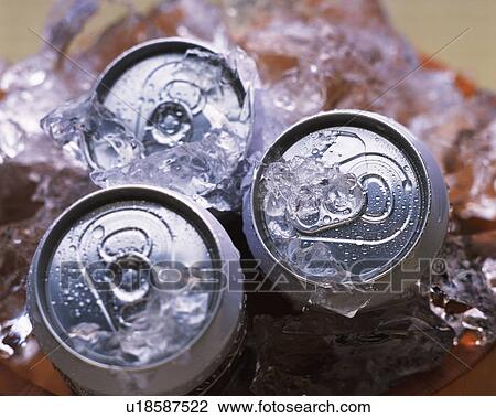Stock Image - Three cans of beer chilling with ice, high angle view, differential focus. Fotosearch