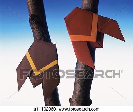 Stock Image - Two Origami cicadas on tree trunks, front view, blue background. Fotosearch