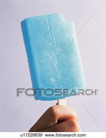 Stock Photo - Woman holding a blue popsicle, front view, white background. Fotosearch