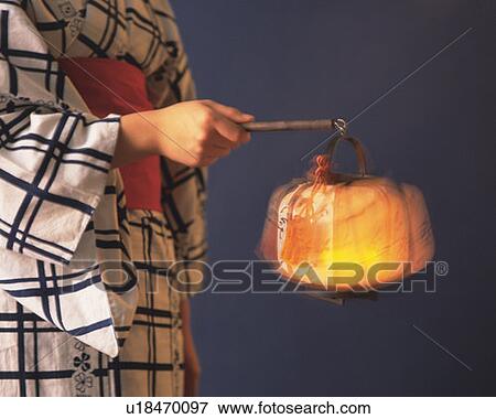Stock Photo - Woman in yukata holding a paper lantern, side view, gray background, blurred motion. Fotosearch