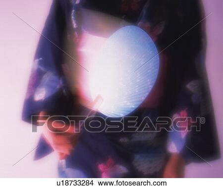 Picture - Woman in yukata waving a Japanese fan, front view, purple background, blurred motion, soft focus. Fotosearch
