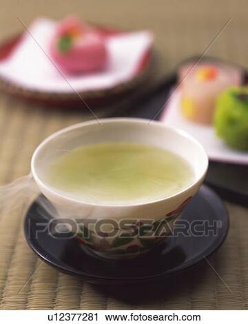 Stock Image - Green tea in a cup and Japanese sweets on plates, high angle view, differential focus. Fotosearch
