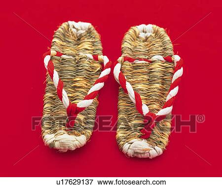Stock Photo - Japanese straw sandals, high angle view, red background. Fotosearch