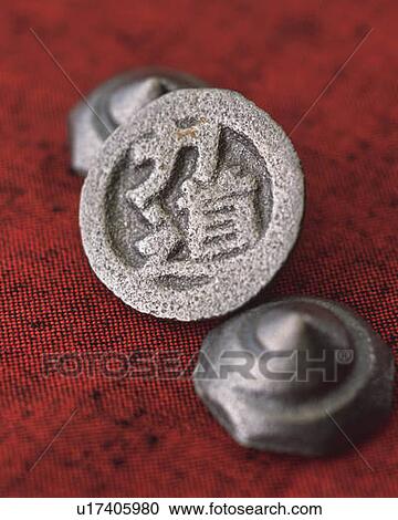 Stock Image - Tiny iron spinning tops on red fabric, high angle view, differential focus. Fotosearch