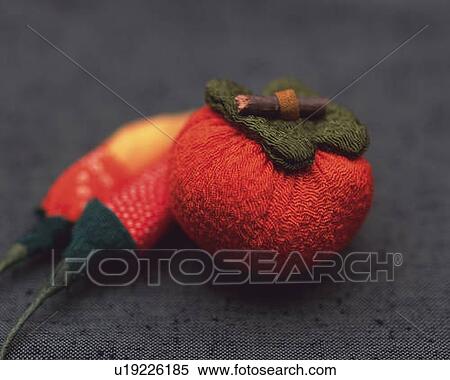 Stock Photography - Toy persimmon and chili peppers on fabric, high angle view, differential focus. Fotosearch
