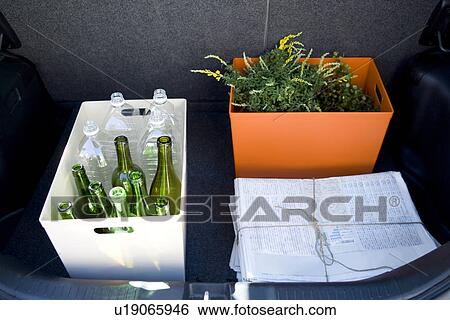 Stock Photograph - Recycling Bottles, Piled Newspaper and Plant in Car Trunk. Fotosearch