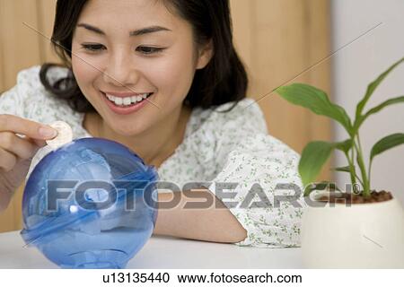 Woman Putting a Coin in Coin Bank View Large Photo Image Stock Image - Woman Putting a Coin in Coin Bank. Fotosearch