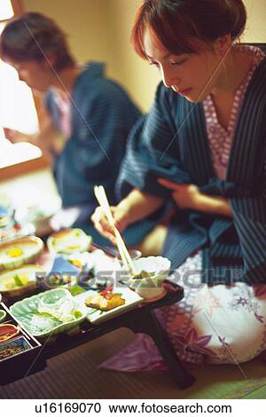 Stock Image - Two Young Woman Eating a Meal. Fotosearch