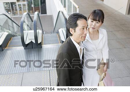 Picture - Japanese Couple, Go Down The Escalator. Fotosearch