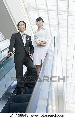 Stock Image - Japanese Couple Going Down The Escalator. Fotosearch