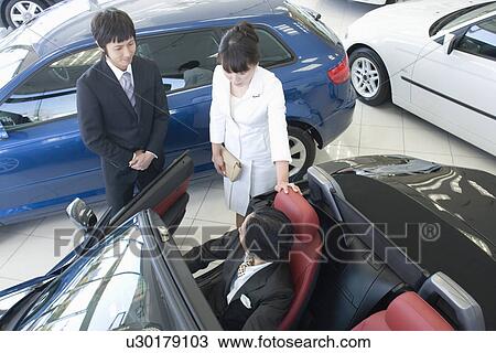 Stock Image - Japanese Couple Looking Of Car. Fotosearch