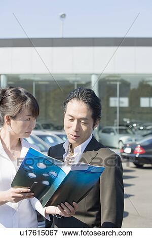Stock Photo - Japanese Couple Looking Of Catalog. Fotosearch