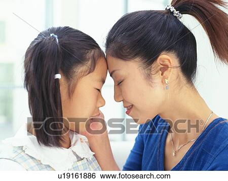 Stock Photograph -  a Mother putting her forehand on daughter's to check for fever, Side View. Fotosearch
