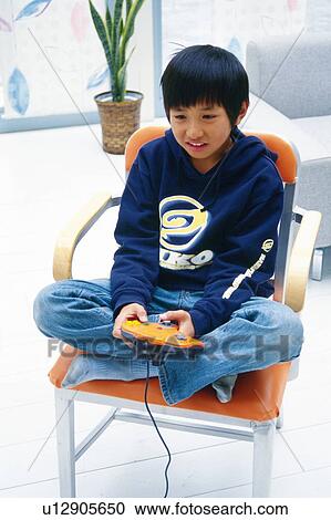 Boy playing a video game on a chair with his Legs Crossed, High Angle View View Large Photo Image Stock Image - Boy playing a video game on a chair with his Legs Crossed, High Angle View. Fotosearch