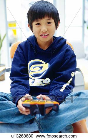 Boy playing video game on a chair with his Legs Crossed, Looking at Camera, Front View View Large Photo Image Stock Image - Boy playing video game on a chair with his Legs Crossed, Looking at Camera, Front View. Fotosearch