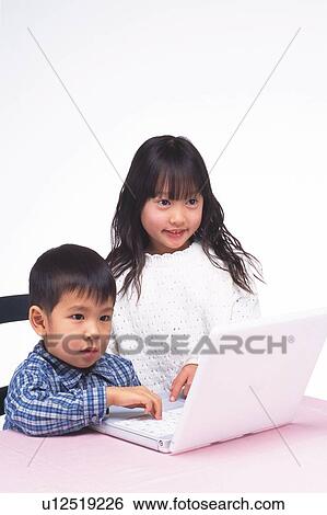 Stock Photograph - Girl and boy looking at the monitor of a laptop on the table, Smiling, Side View. Fotosearch