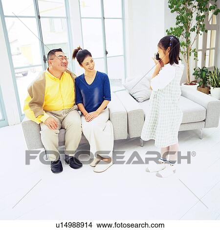 Girl taking a picture of her parents in the Living room, Smiling, Side View, High Angle View View Large Photo Image Picture - Girl taking a picture of her parents in the Living room, Smiling, Side View, High Angle View. Fotosearch