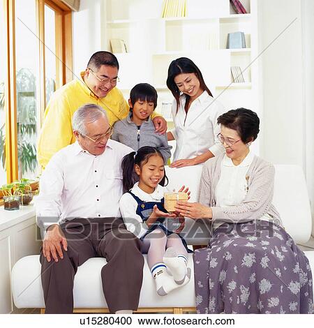 Japanese family in the living room the Grandmother passing a gift to her granddaughter, Smiling, Front View View Large Photo Image Stock Image - Japanese family in the living room the Grandmother passing a gift to her granddaughter, Smiling, Front View. Fotosearch