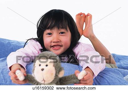 Little Girl lying on a quilt and holding a monkey doll, looking at camera, Smiling, Front View, Differential Focus View Large Photo Image Stock Image - Little Girl lying on a quilt and holding a monkey doll, looking at camera, Smiling, Front View, Differential Focus. Fotosearch