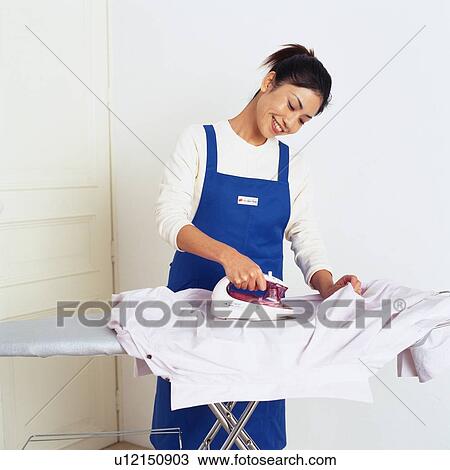 Stock Image - Mid Adult Woman ironing a shirt, Smiling, Low Angle View. Fotosearch