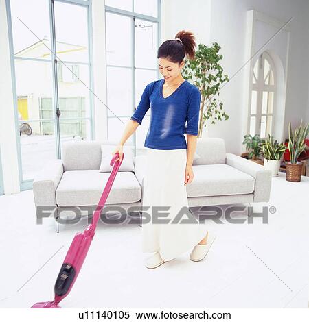 Mid Adult Woman vacuuming the living room, Looking Down, Low Angle View View Large Photo Image Stock Photography - Mid Adult Woman vacuuming the living room, Looking Down, Low Angle View. Fotosearch