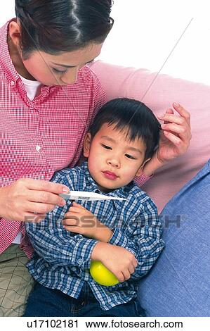Mother checking the temperature of her son who is holding a yellow ball, High Angle View View Large Photo Image Stock Image - Mother checking the temperature of her son who is holding a yellow ball, High Angle View . Fotosearch