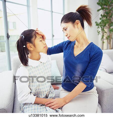 Mother putting her hand on daughter's forehead to check for fever, Side View View Large Photo Image Stock Photography - Mother putting her hand on daughter's forehead to check for fever, Side View. Fotosearch