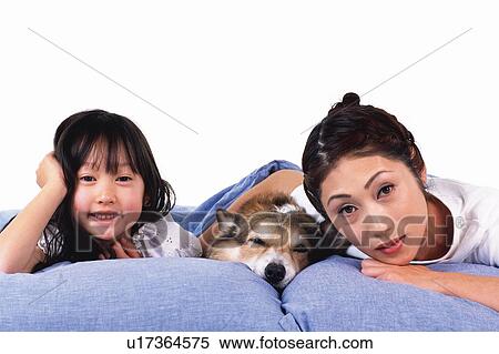Stock Photography - Portrait of a Mother and her daughter and their Pembroke Welsh Corgi, all lying in Bed Together, Front View, Looking at Camera. Fotosearch