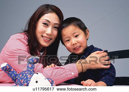 Stock Photo - Portrait of a Mother and her Son, the Mother holding the shoulders of his Son, Smiling, Looking at Camera, Front View. Fotosearch