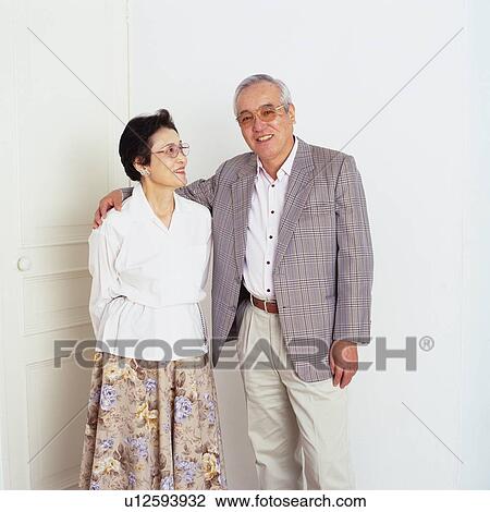 Portrait of a Senior Couple, the man putting his arm around his Wife, Looking at Camera, Smiling, Front View View Large Photo Image Stock Image - Portrait of a Senior Couple, the man putting his arm around his Wife, Looking at Camera, Smiling, Front View. Fotosearch