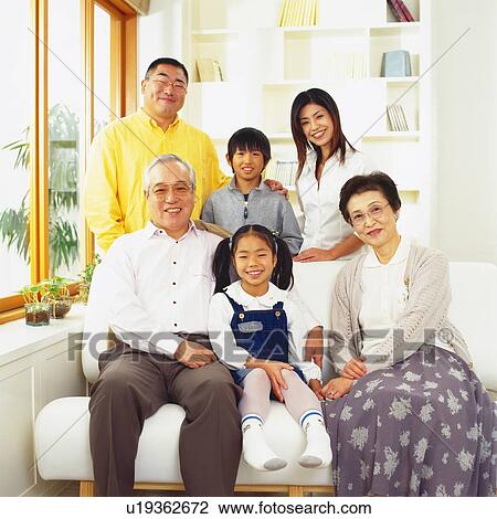 Stock Image - Portrait of Japanese family, gathered in the Living Room, Looking at Camera, Smiling, Front View. Fotosearch
