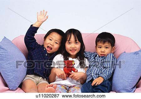 Portrait of Two Little Boys and One Girl in the Middle, Sitting on a Sofa, Smiling, Looking at Camera, Front View View Large Photo Image Stock Photo - Portrait of Two Little Boys and One Girl in the Middle, Sitting on a Sofa, Smiling, Looking at Camera, Front View. Fotosearch