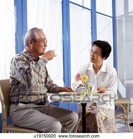 Stock Image - Senior Couple Having a Conversation During a Cup of Coffee, Smiling, Low Angle View. Fotosearch