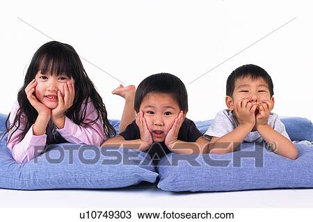 Three children lying on Blue Pillows, putting elbows on pillows, Resting their Faces on their Hands, Looking at Camera, Front View View Large Photo Image Stock Image - Three children lying on Blue Pillows, putting elbows on pillows, Resting their Faces on their Hands, Looking at Camera, Front View. Fotosearch
