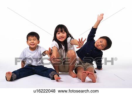 Stock Photo - Three Little children Making Poses on a White-colored Floor, smiling, Looking at Camera, Front View. Fotosearch
