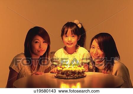 Two Young Adult Women and a Little girl sitting in front of a birthday cake with burning candles, Smiling, Looking at Camera, Front View View Large Photo Image Stock Image - Two Young Adult Women and a Little girl sitting in front of a birthday cake with burning candles, Smiling, Looking at Camera, Front View. Fotosearch