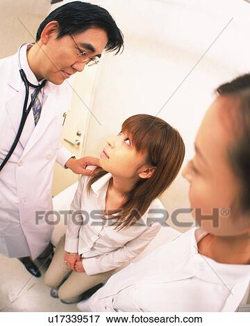 Stock Photo - Doctor examining patient, nurse standing nearby, watching. Fotosearch