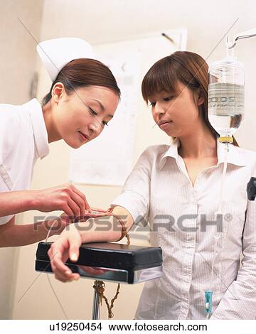 Nurse inserting intravenous drip in a Patient's Arm View Large Photo Image Picture - Nurse inserting intravenous drip in a Patient's Arm . Fotosearch