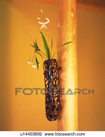 Stock Image - Flowers in vase put on wooden pole, side view, Japan, differential focus. Fotosearch