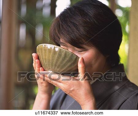 Stock Photo - Woman in kimono drinking a cup of tea at tea ceremony, close up, Japan, differential focus. Fotosearch