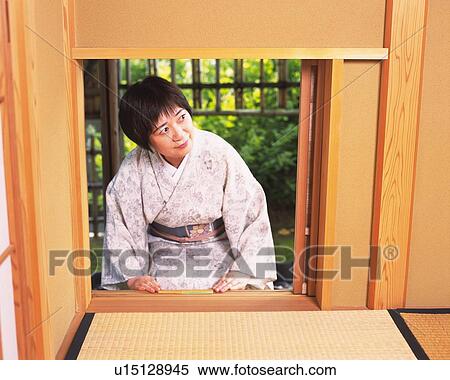 Stock Photography - Woman in kimono entering into the tea room from Nijiriguchi, front view, Japan. Fotosearch
